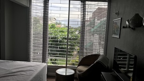 Un dormitorio con una cama, una silla, una mesita y un televisor.