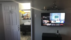 Una sala de estar con un televisor montado en la pared mostrando la interfaz de un servicio de streaming.