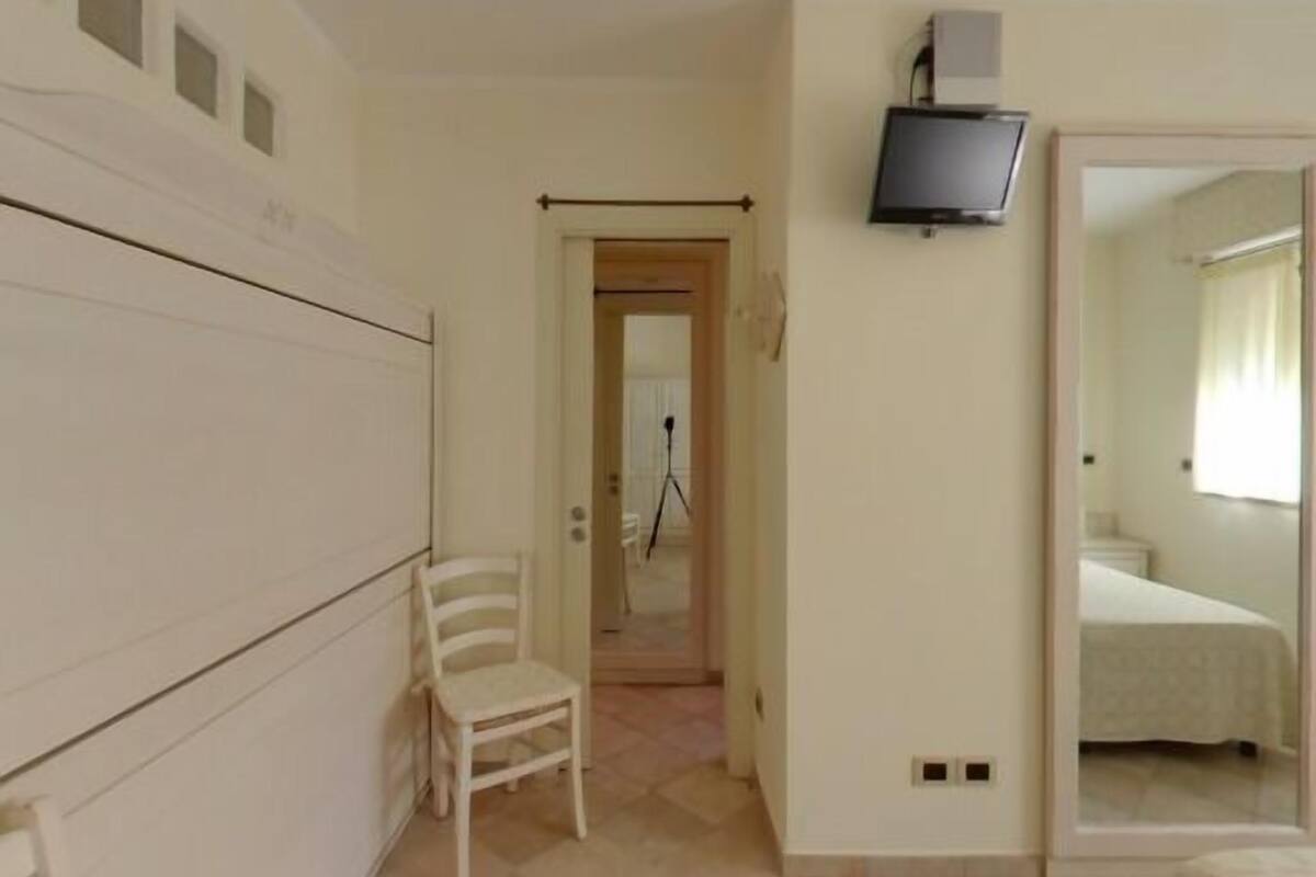 Une chambre d’hôtel comprenant un lit, un téléviseur fixé au mur, une chaise et une armoire.