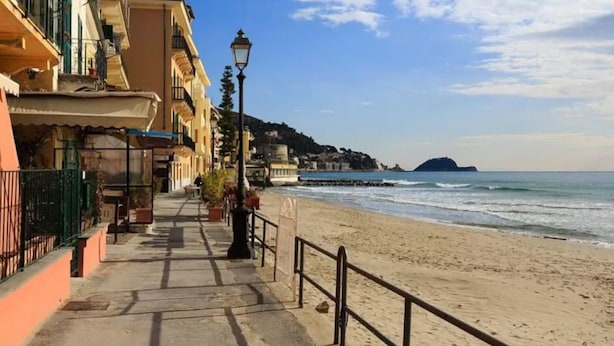 Un camino costero con edificios a un lado y una playa al otro.