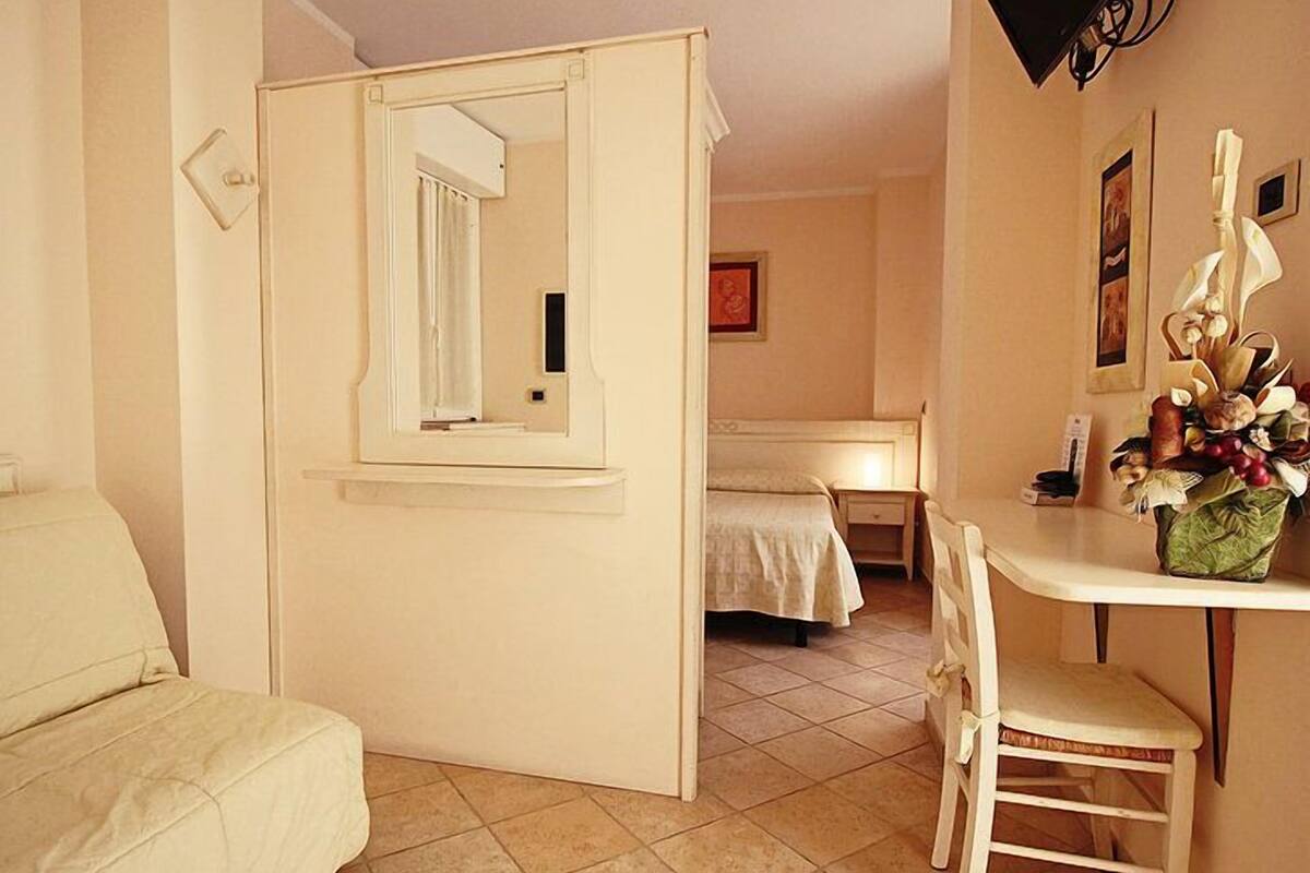 Une petite pièce comprenant un lit, un bureau, une chaise et un miroir.