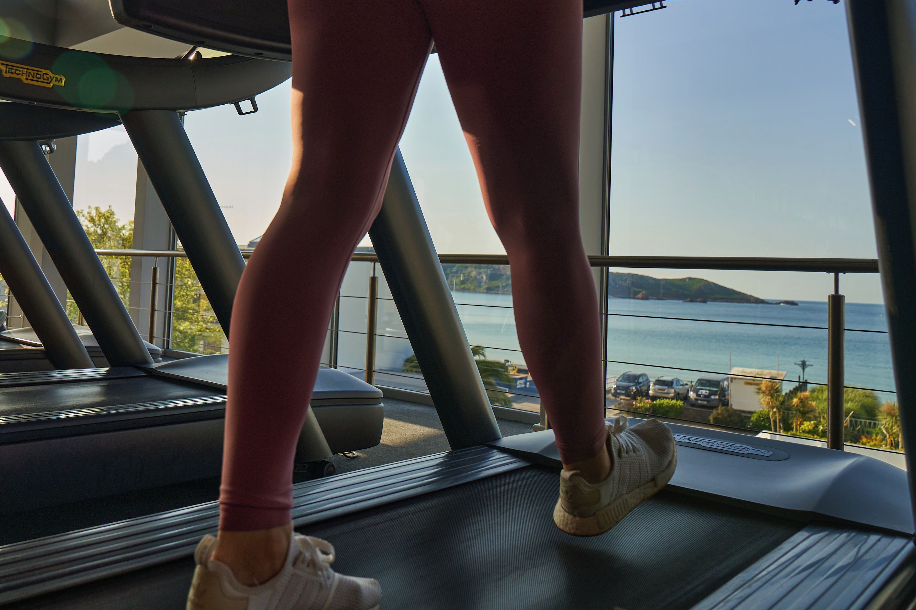 A treadmill with a view of a body of water and hills in the background.