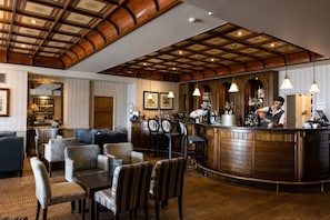 A bar area with wooden bar counter, hanging lights, and seating with upholstered chairs. - St Brelades Bay Hotel (St. Brelade)