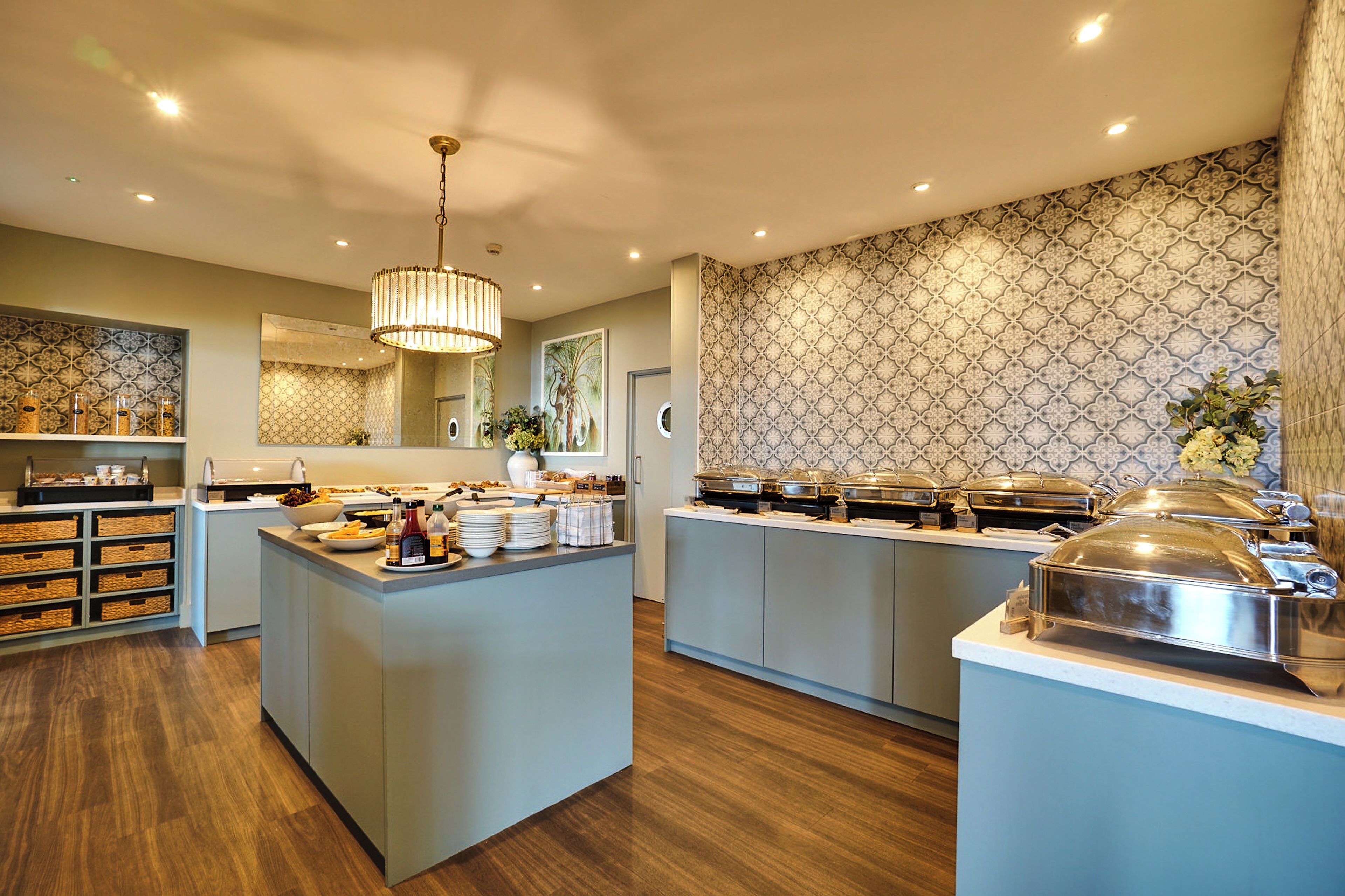 Une cuisine moderne dotée d’un îlot central, d’un espace buffet et de motifs décoratifs sur les murs.