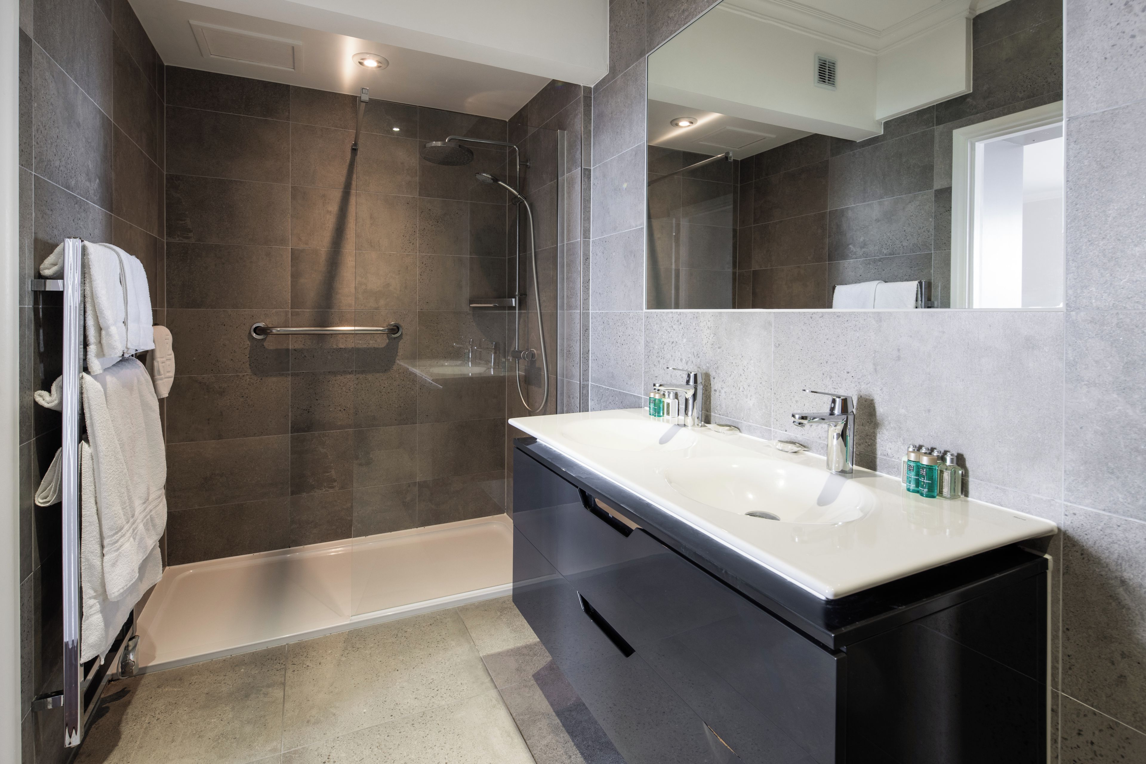 A modern bathroom with a walk-in shower, a bathtub, and a vanity with a sink.