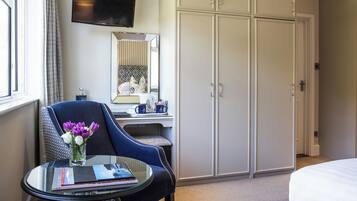 A hotel room with a bed, a desk with a chair, a television, and a wardrobe.