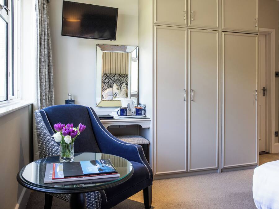A hotel room with a bed, a desk with a chair, a television, and a wardrobe.