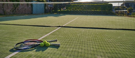 A tennis court with a net, tennis rackets, and balls.