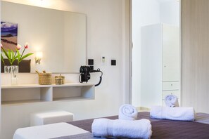 Une chambre d’hôtel avec un lit, une table de chevet, un miroir, un sèche-cheveux fixé au mur et une serviette sur le sol.