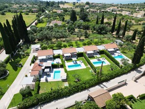 Un quartier résidentiel composé de plusieurs maisons, chacune dotée d’une piscine et d’un jardin.