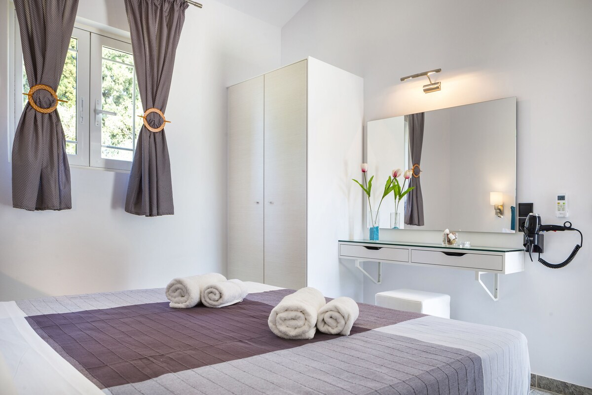 Une chambre d’hôtel avec un lit, un grand miroir, un bureau et une armoire.