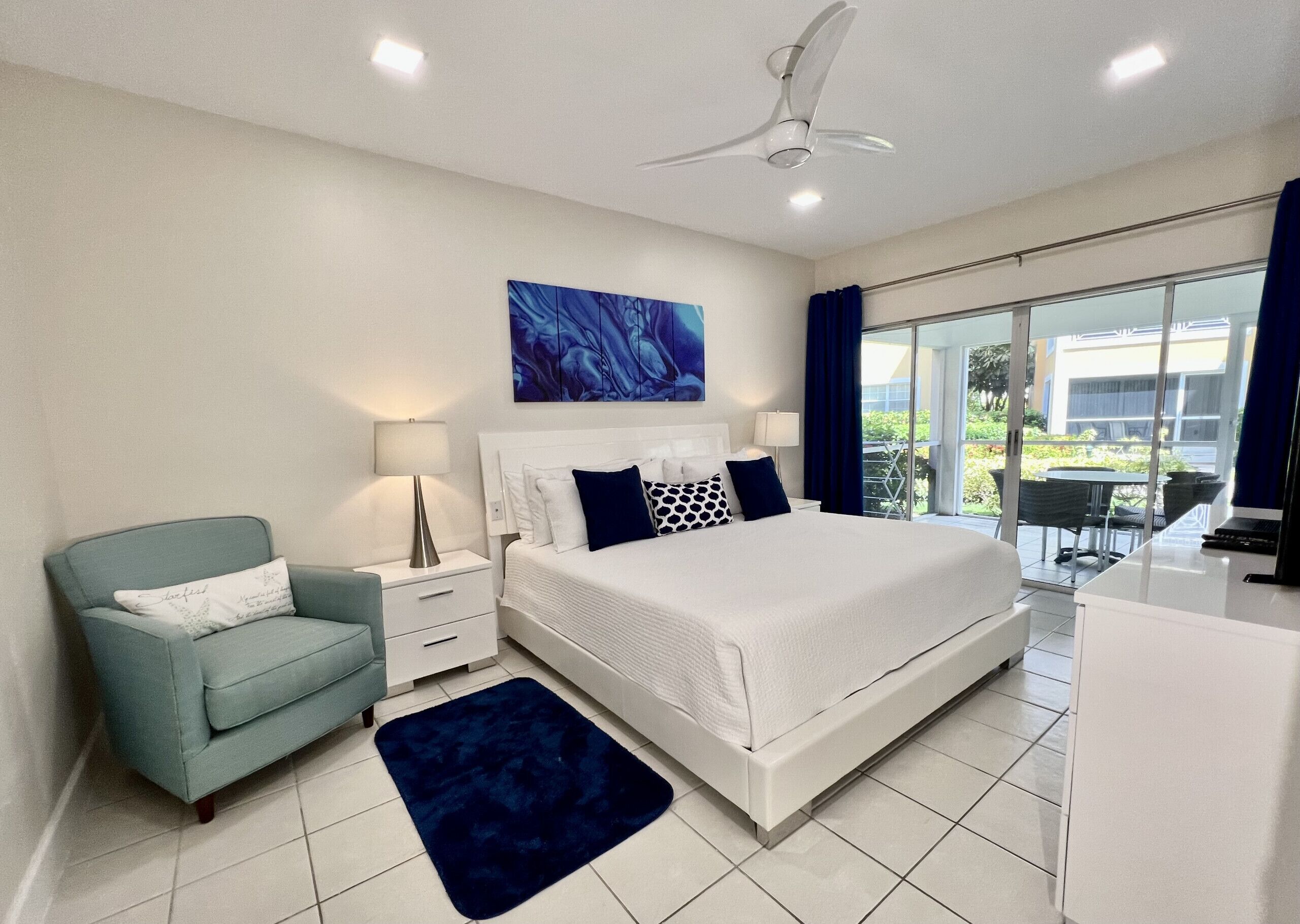 Une chambre à coucher moderne avec un grand lit, un bureau, une chaise et une vue sur l’extérieur.
