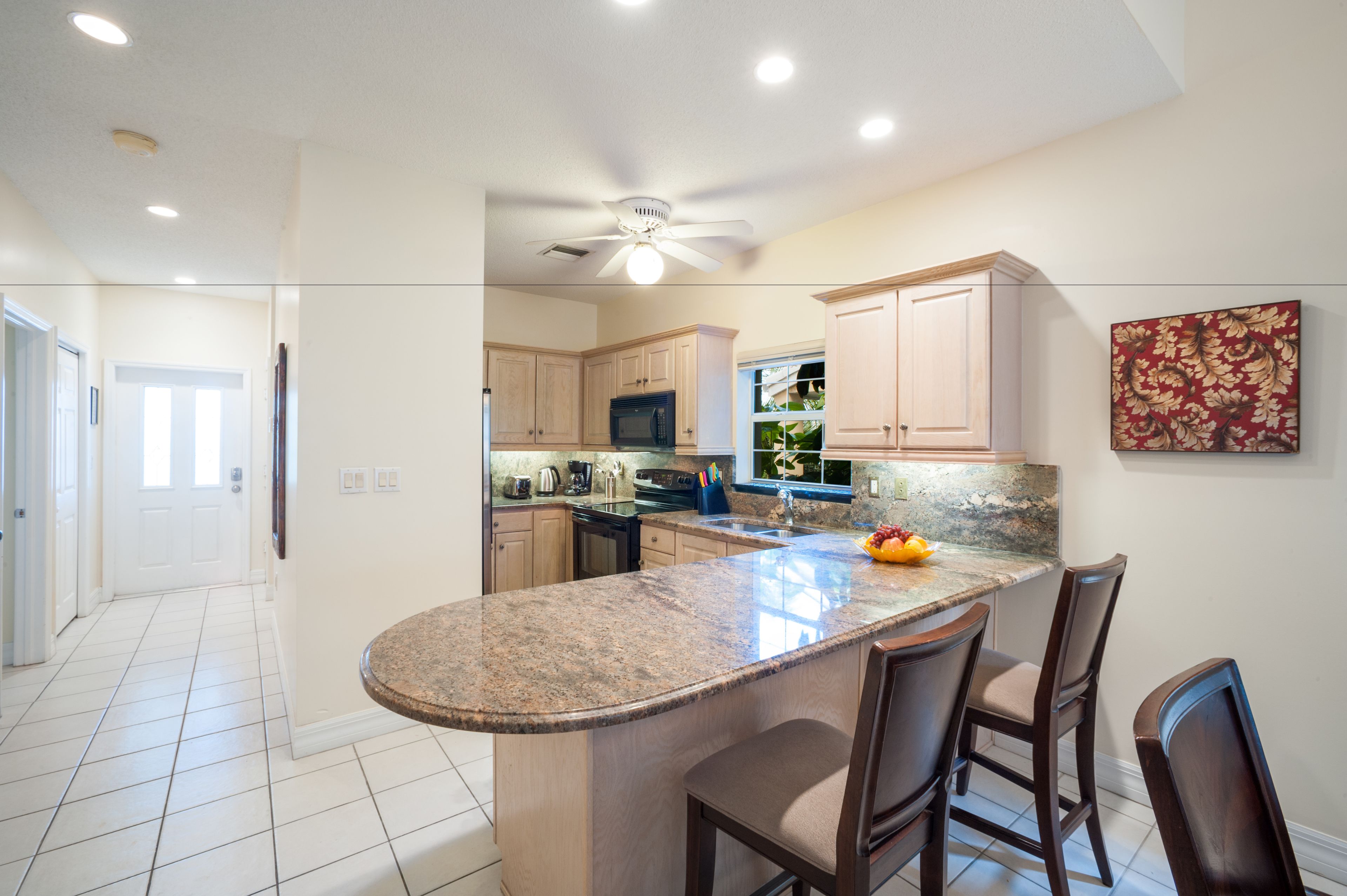 A kitchen with a granite island, wooden cabinets, and a ceiling fan.