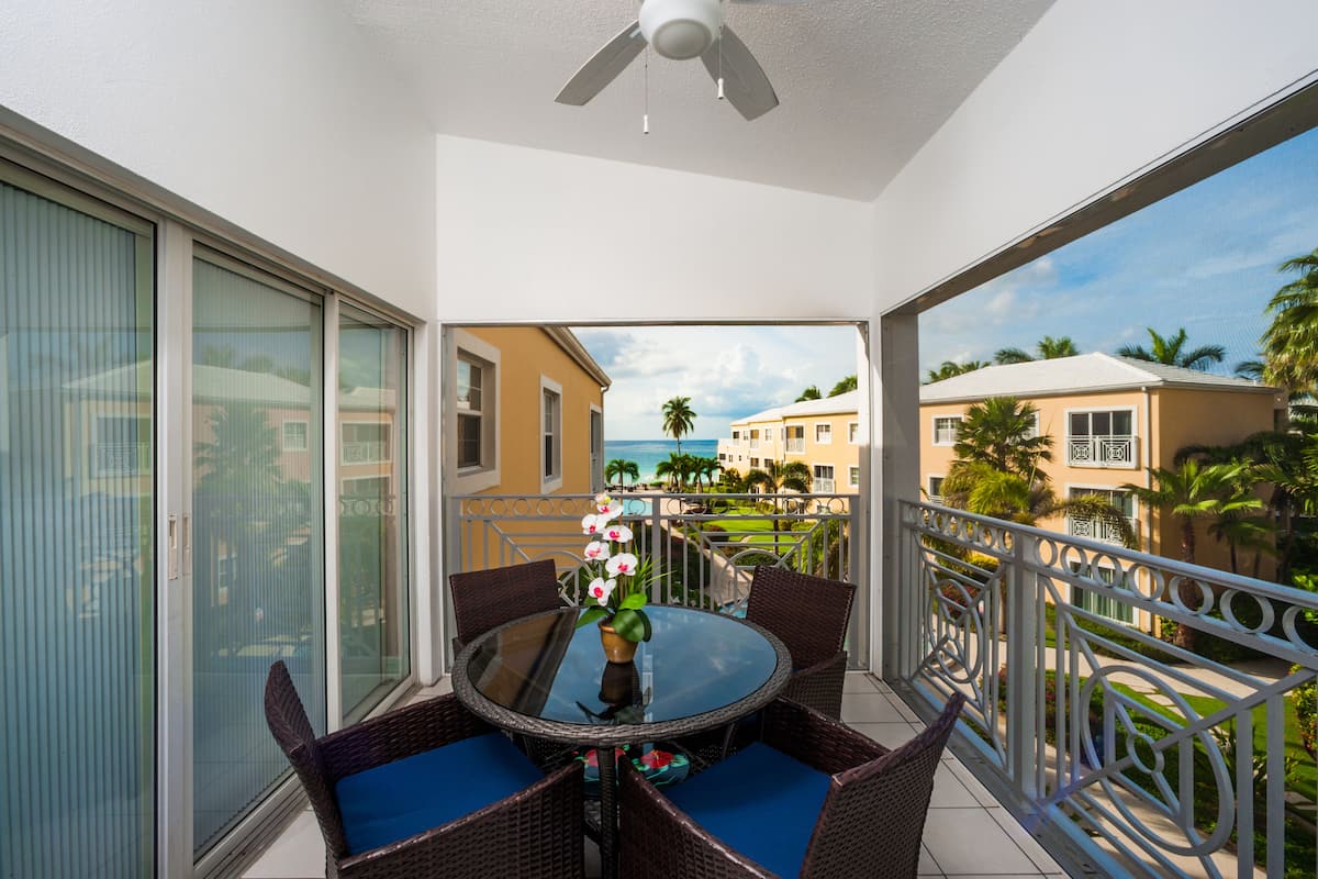 A balcony with a glass door, a round table with chairs, and a ceiling fan.