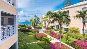 A hotel with a pool, palm trees, and a view of the ocean. - Regal Beach Club (Seven Mile Beach)