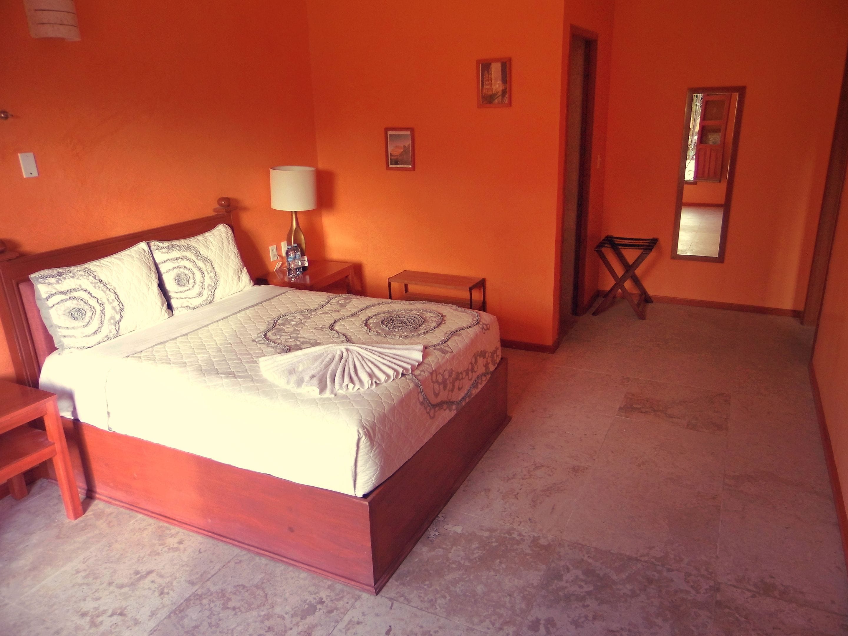 A bedroom with a bed, nightstand, lamp, and a small table.