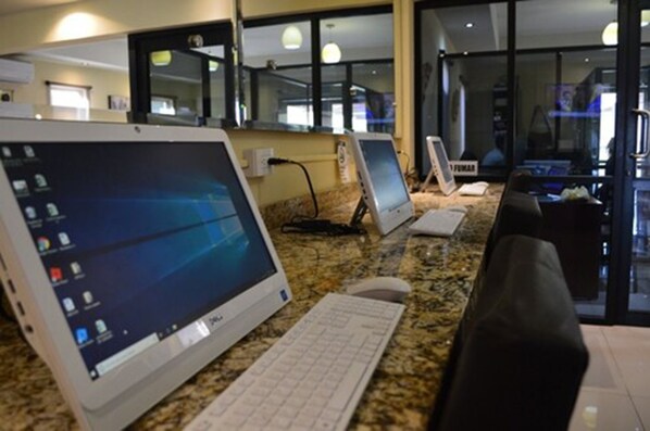 A hotel workspace with multiple desktop computers, a keyboard, and a chair. - Hotel San Ignacio Inn (Torreón)
