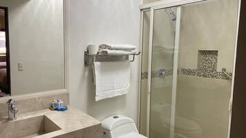 A bathroom with a sink, toilet, and glass shower enclosure.