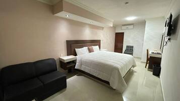Una habitación de hotel con una cama, un sofá negro, un escritorio y una silla.