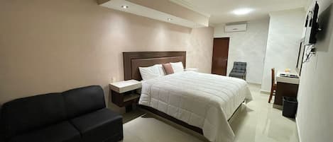 Una habitación de hotel con una cama, un sofá negro, un escritorio y una silla.