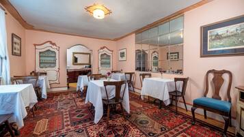 A room with tables set for dining, a mirror, and patterned rugs.