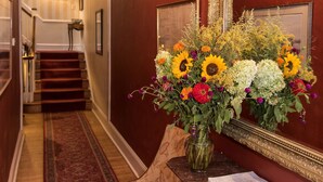 A hallway with a red carpet, a wooden bench, a vase of flowers, and a mirror on the wall. - La Reserve on Pine (Philadelphia)