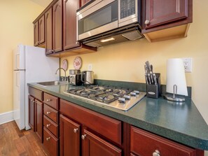 A kitchen with wooden cabinets, a stainless steel stove, a microwave, and a refrigerator. - La Reserve on Pine (Philadelphia)