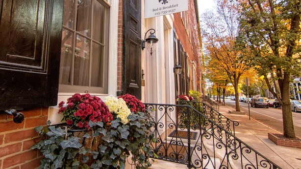 A hotel entrance with a sign for 'La Réserve Bed & Breakfast' and a flower box with red and white flowers. - La Reserve on Pine (Philadelphia)