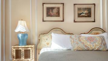 Une chambre à coucher avec un lit, une table de chevet avec une lampe, deux tableaux encadrés au mur et une tête de lit décorative.