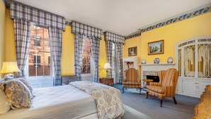 A bedroom with a bed, two chairs, a fireplace, and a view of the outside. - La Reserve on Pine (Philadelphia)