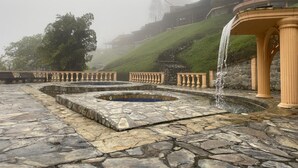 A stone fountain with a water feature, surrounded by a stone-paved area with benches and railings. - Finca Hotel Rancho San Antonio (Salento)