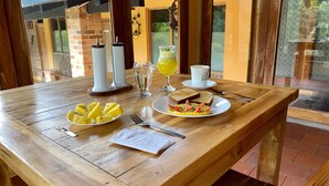 A wooden table with breakfast items including toast, eggs, and pineapple slices, along with a glass of orange juice and a cup of coffee. - Finca Hotel Rancho San Antonio (Salento)