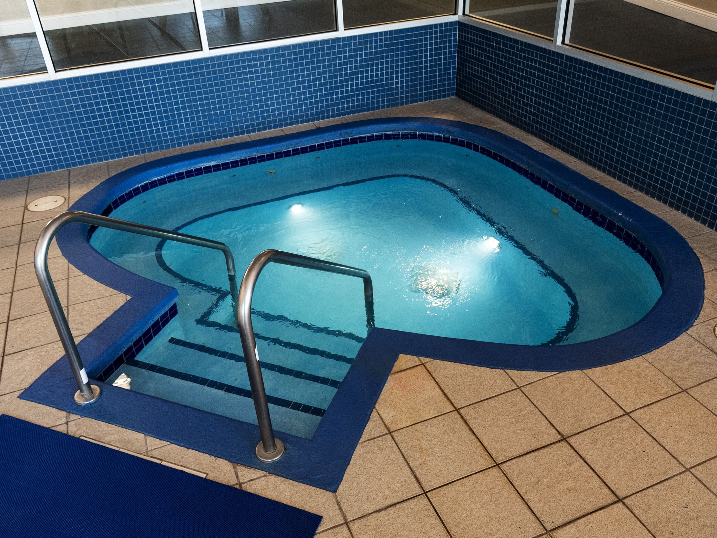 A swimming pool with a blue tiled border and a metal ladder.