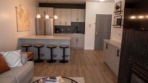A modern kitchen with a central island, bar stools, and a dining area with a sofa and coffee table. - Delavan Lake Resort (Delavan)