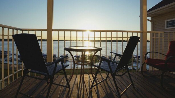 A wooden deck with a table and chairs facing a body of water. - Delavan Lake Resort (Delavan)