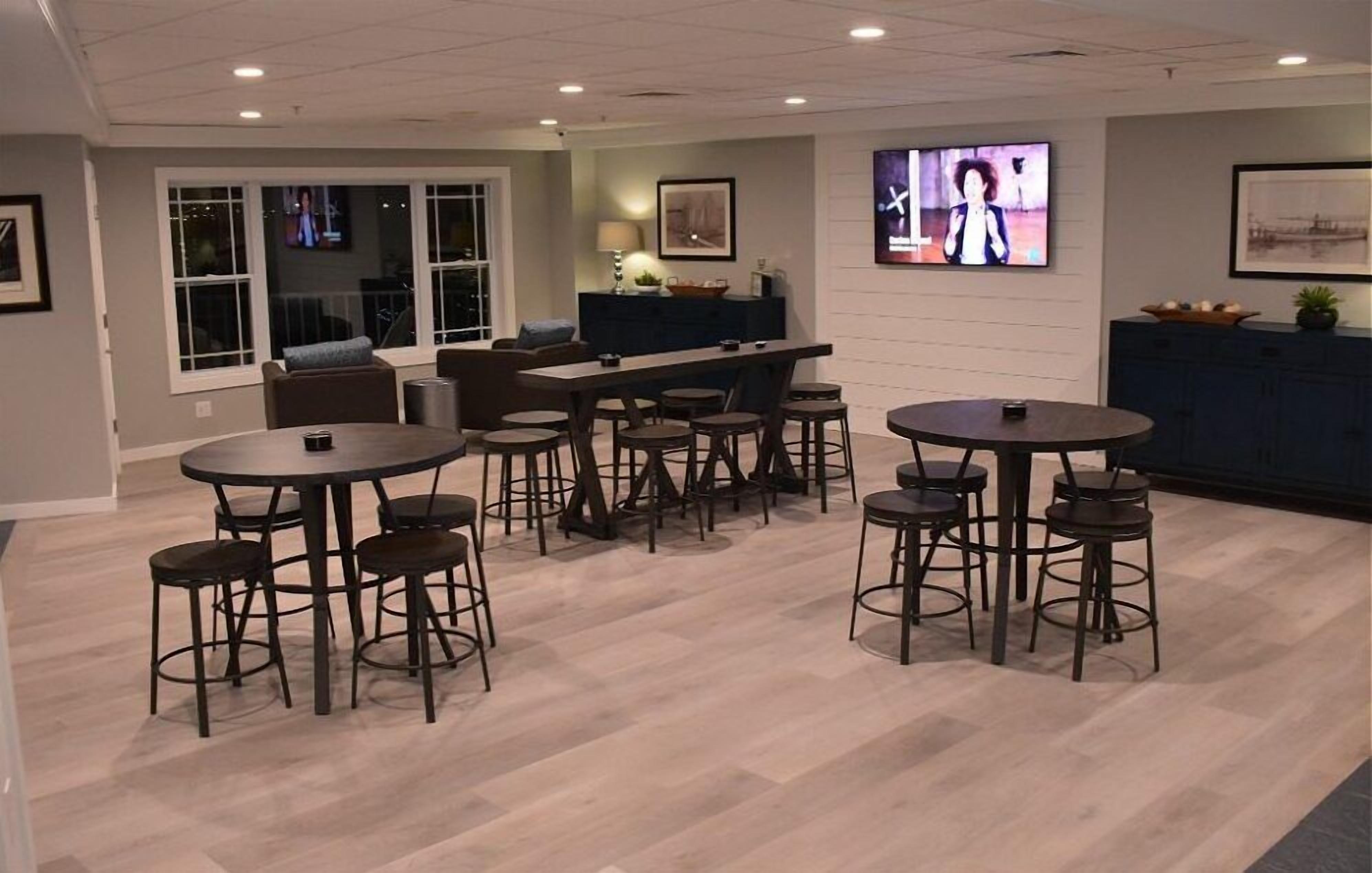 Un espace bar moderne offrant différentes options de sièges, notamment des tables rondes et des tabourets de bar.