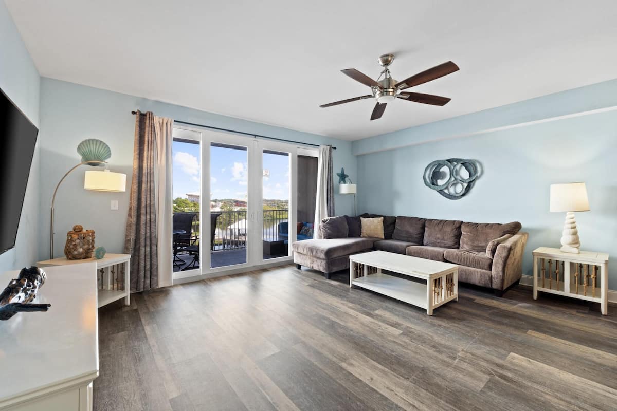 A spacious living room with a sofa, coffee table, and a ceiling fan.