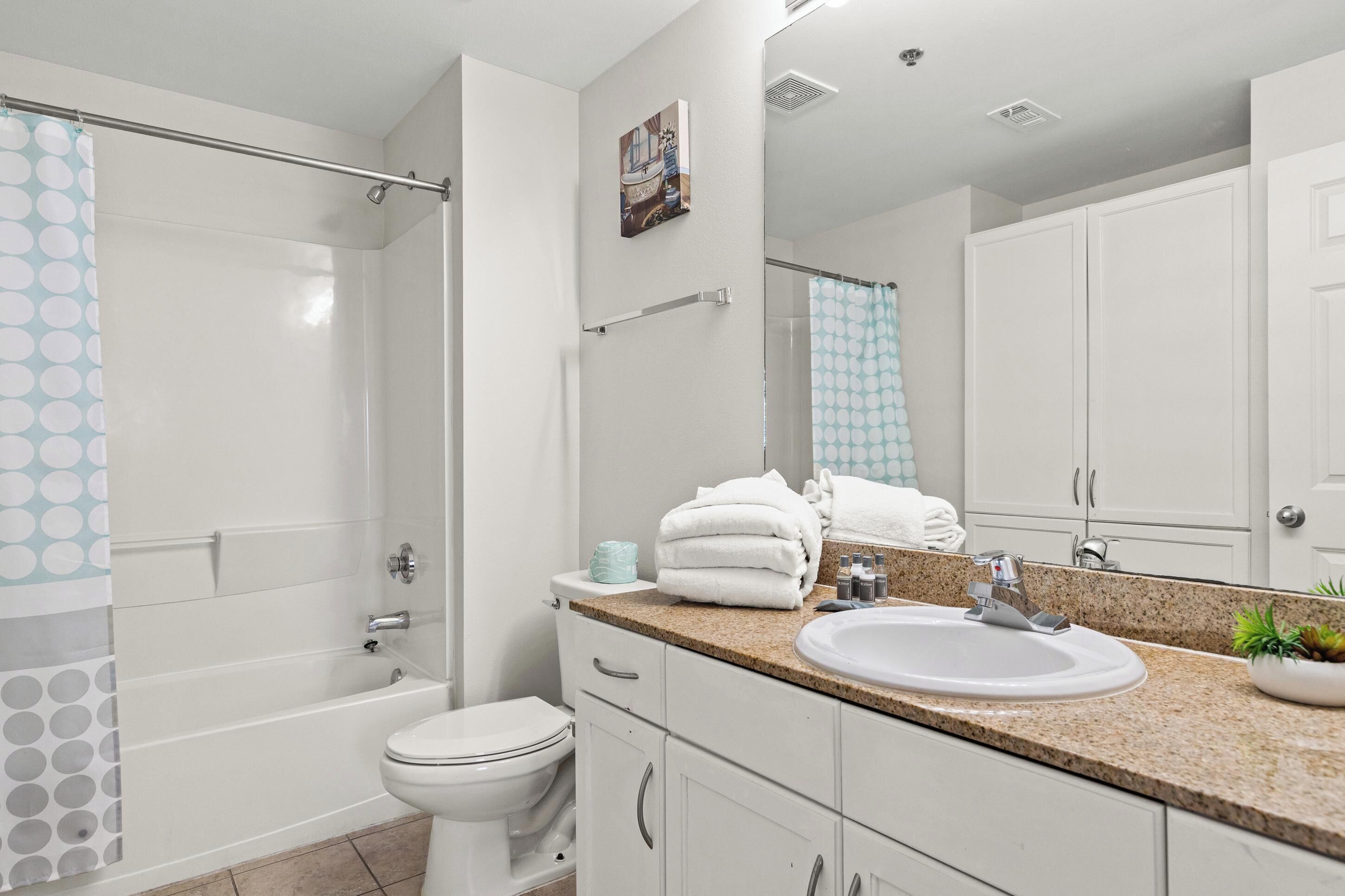 A modern bathroom with a shower, toilet, sink, and a large mirror.