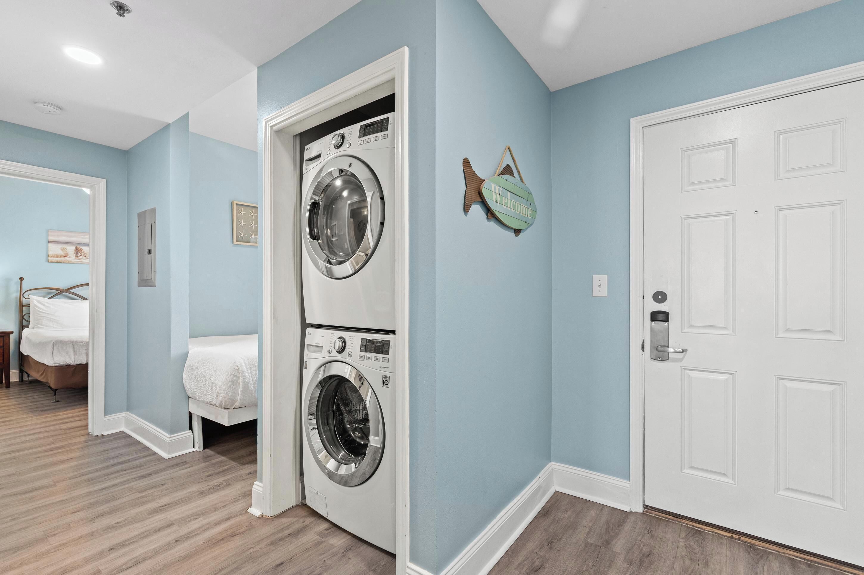 A laundry room with two washing machines, a bed, a door, and a wall-mounted fish decoration.