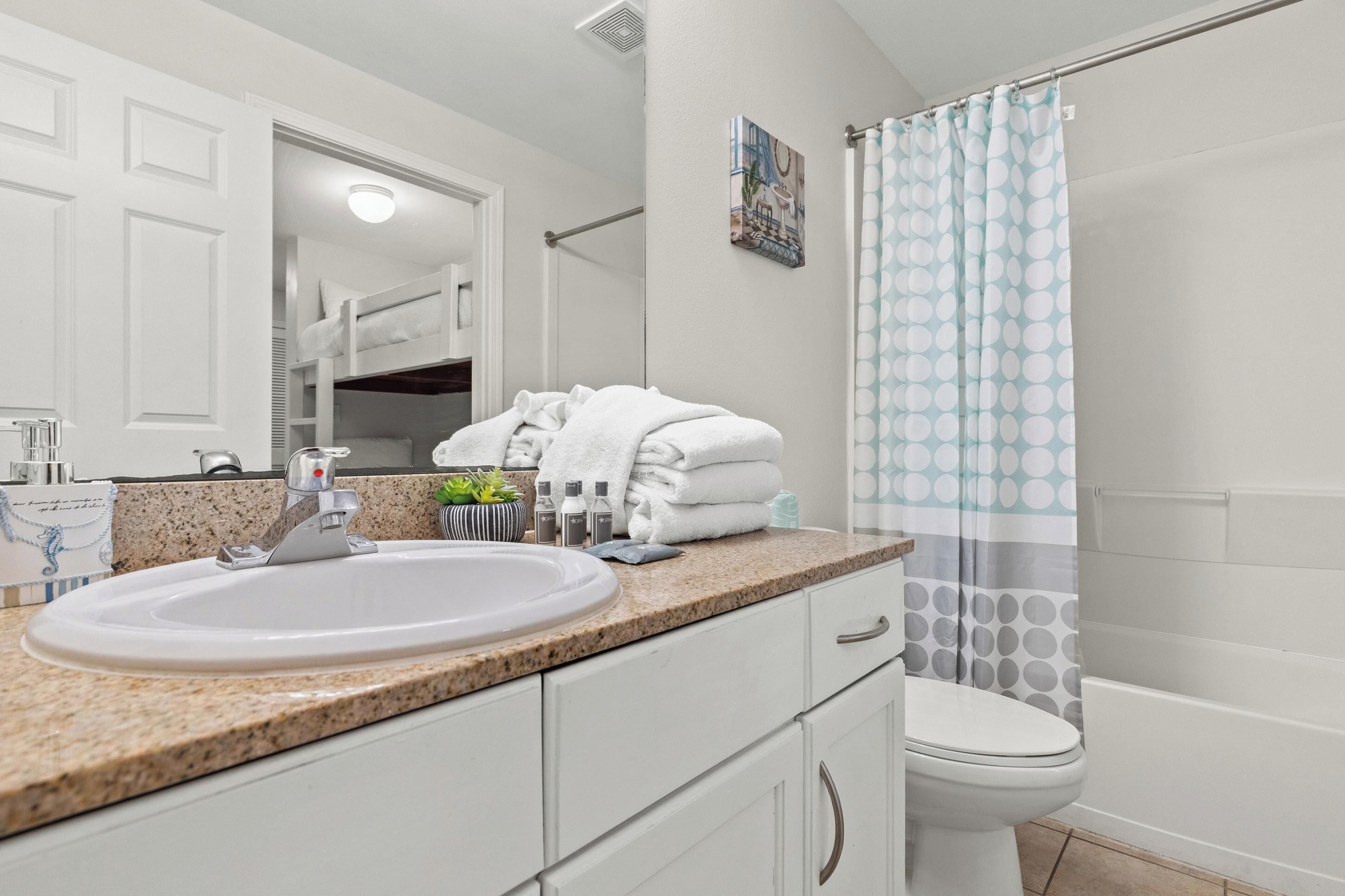 A bathroom with a sink, toilet, and shower curtain.