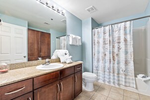 A bathroom with a vanity, sink, mirror, and shower curtain.