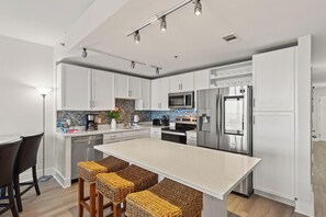 A modern kitchen with white cabinets, stainless steel appliances, and a central island with bar stools. - Laketown Wharf Resort by Panhandle Getaways (Panama City Beach)