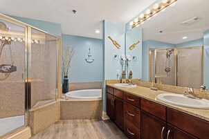 A bathroom with two sinks, a bathtub, a shower, and a vanity with drawers.