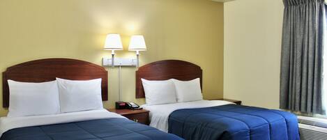 A hotel room with two beds, a nightstand with a phone, wall-mounted lamps, and a window with curtains.
