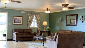 A living room with two sofas, a coffee table, a lamp, and a ceiling fan. - Candlelight Inn & Suites Hwy 69 near McAlester (McAlester)