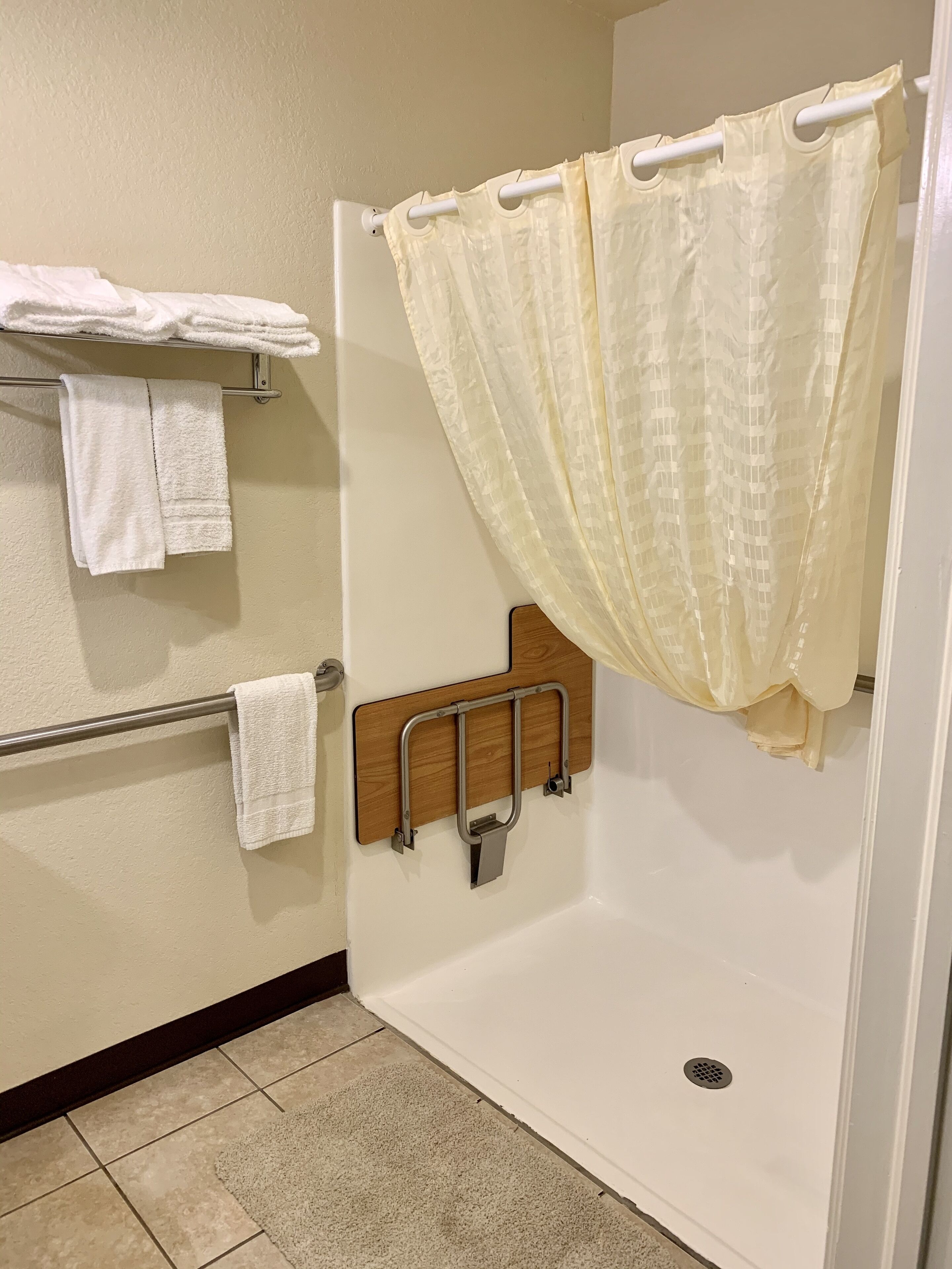 A shower area with a grab bar, a towel rack, and a shower curtain.