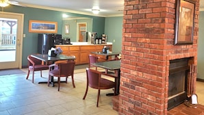 A kitchen with a brick fireplace, a dining area with a table and chairs, and a refrigerator. - Candlelight Inn & Suites Hwy 69 near McAlester (McAlester)