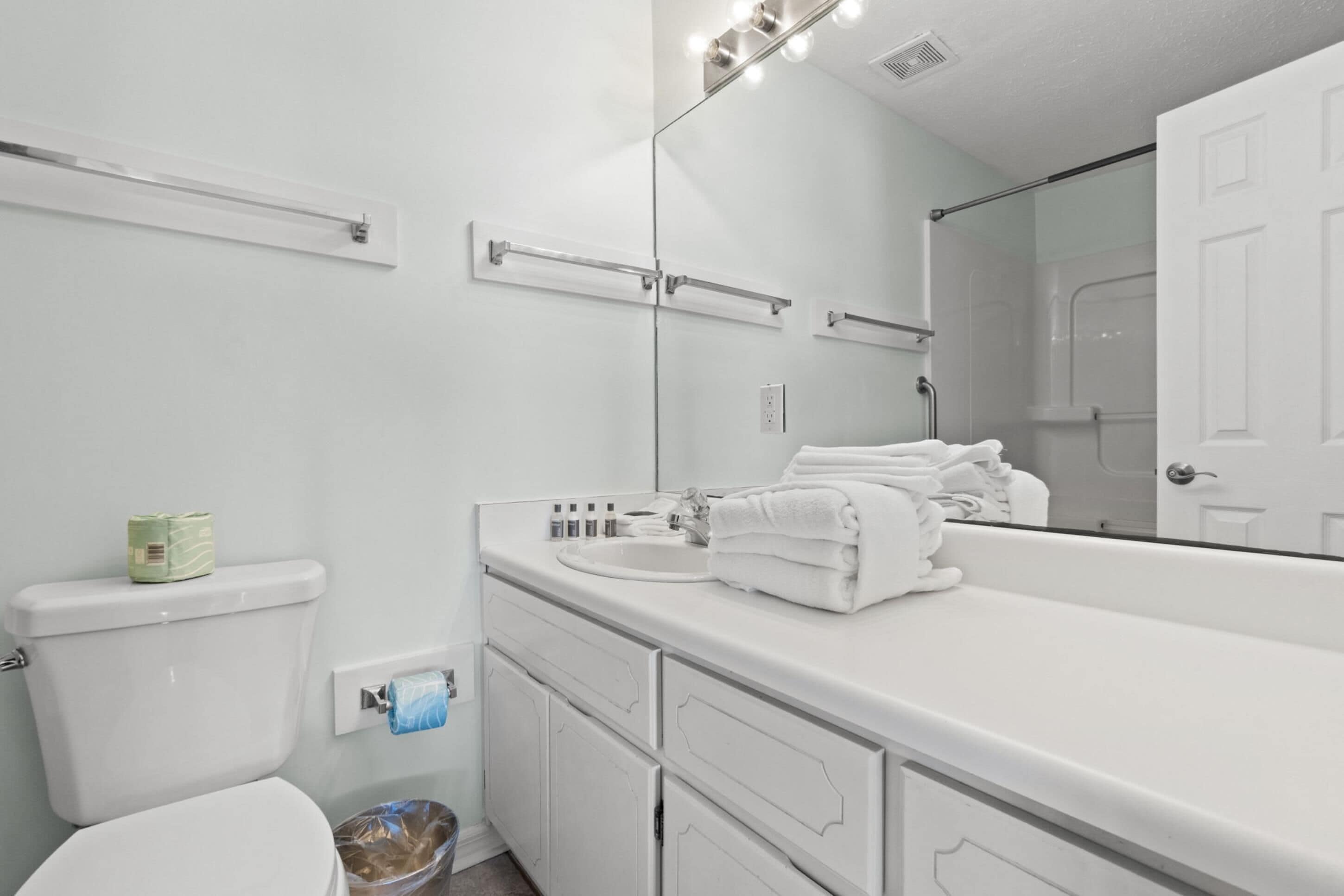 Een badkamer met toilet, wastafel en spiegel.