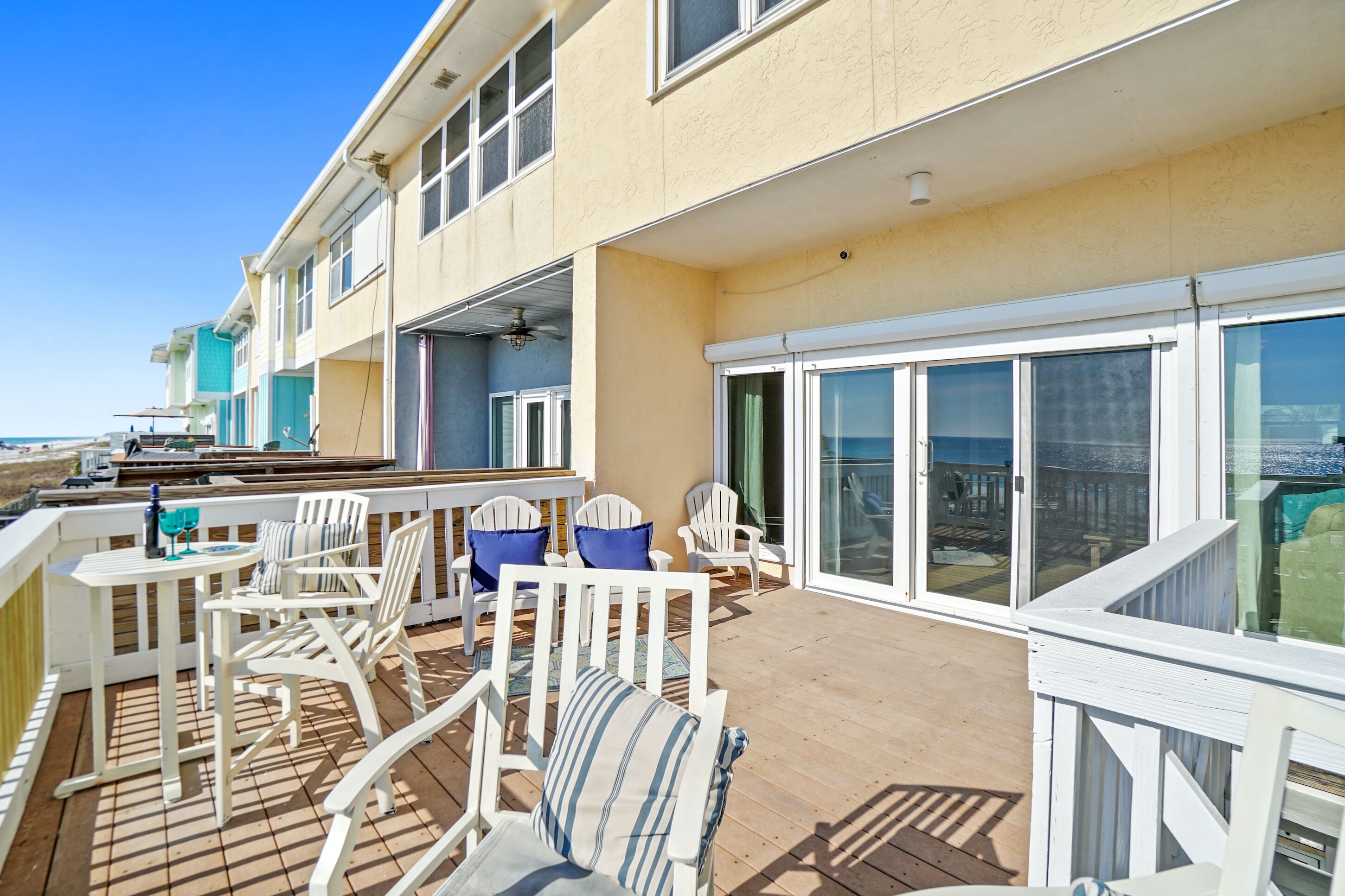 En overdækket terrasse med hvide møbler, et poolbord og havudsigt.