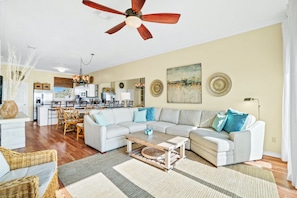 A spacious living room with a large sectional sofa, a coffee table, and a dining area with chairs and a table. - Beachside West Panama City Beach by Panhandle Getaways (Panama City Beach)